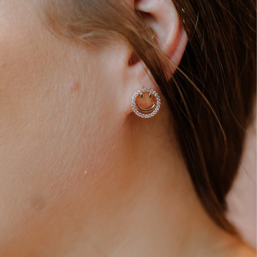 stud earrings in the shape of a gold happy face surrounded by sparkling rhinestones