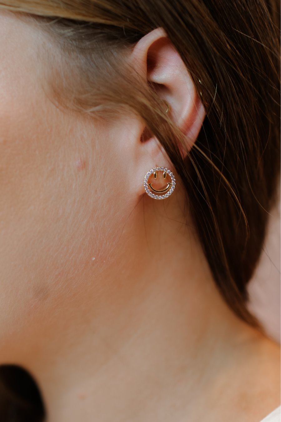 stud earrings in the shape of an open gold happy face surrounded by sparkling rhinestones