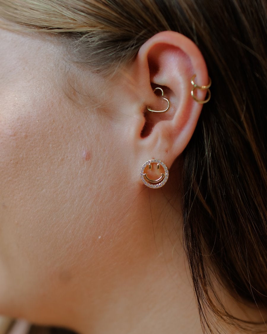 stud earrings in the shape of a gold happy face surrounded by sparkling rhinestones