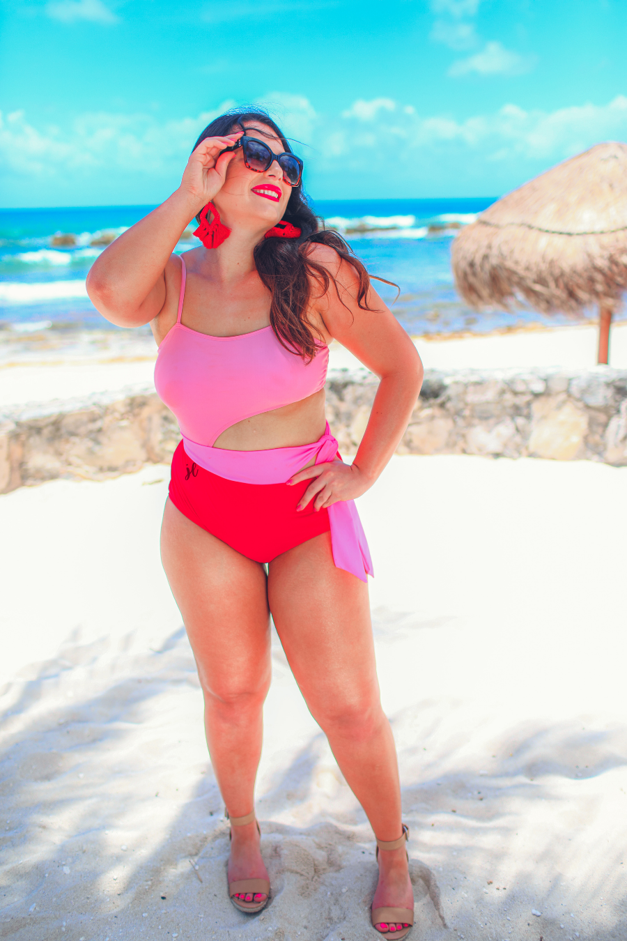 two-tone one-piece swimsuit made of stretchy material with adjustable spaghetti straps that can crisscross in back, a side cutout with a wraparound tie, and removable padding