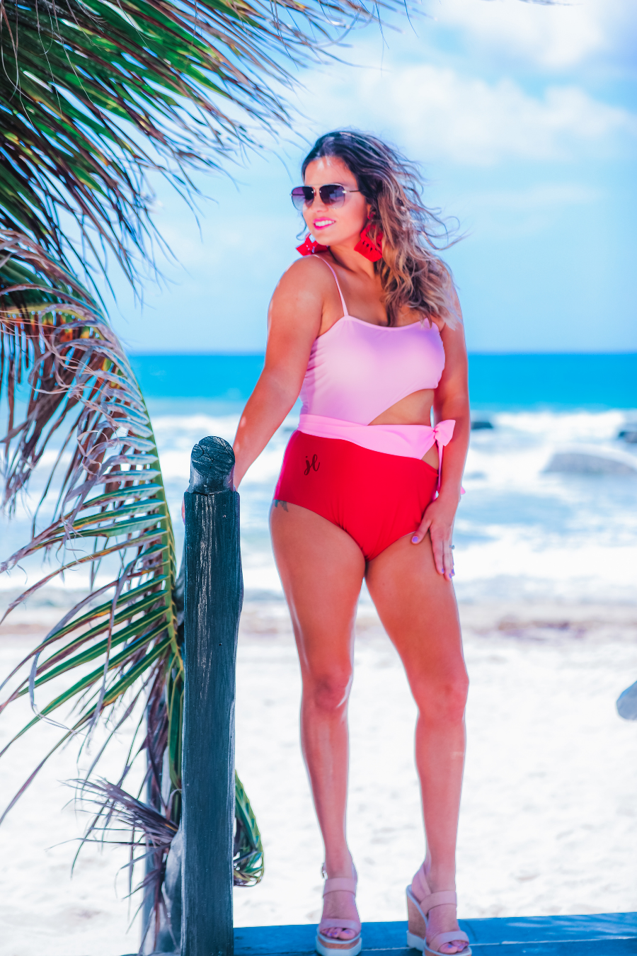 two-tone one-piece swimsuit made of stretchy material with adjustable spaghetti straps that can crisscross in back, a side cutout with a wraparound tie, and removable padding