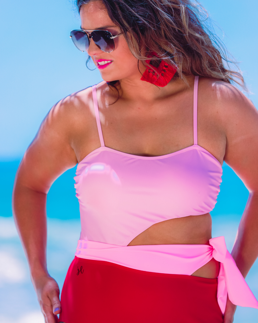 two-tone one-piece swimsuit made of stretchy material with adjustable spaghetti straps that can crisscross in back, a side cutout with a wraparound tie, and removable padding