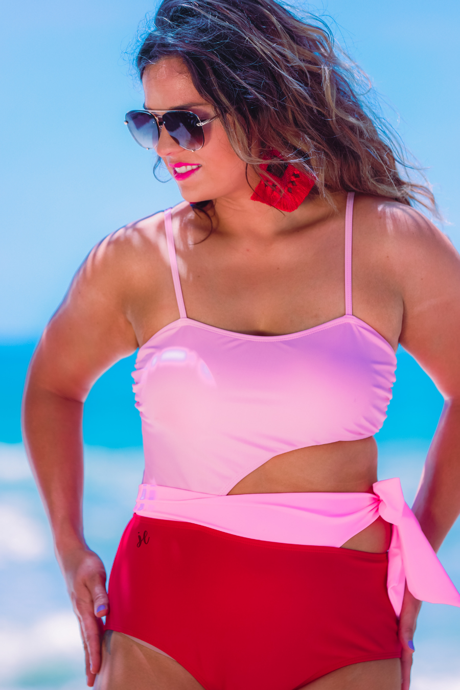 two-tone one-piece swimsuit made of stretchy material with adjustable spaghetti straps that can crisscross in back, a side cutout with a wraparound tie, and removable padding