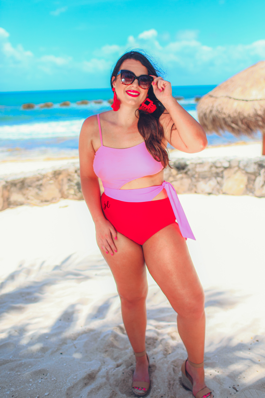 two-tone one-piece swimsuit made of stretchy material with adjustable spaghetti straps that can crisscross in back, a side cutout with a wraparound tie, and removable padding