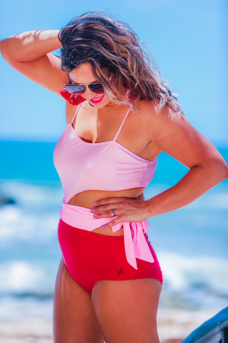 two-tone one-piece swimsuit made of stretchy material with adjustable spaghetti straps that can crisscross in back, a side cutout with a wraparound tie, and removable padding