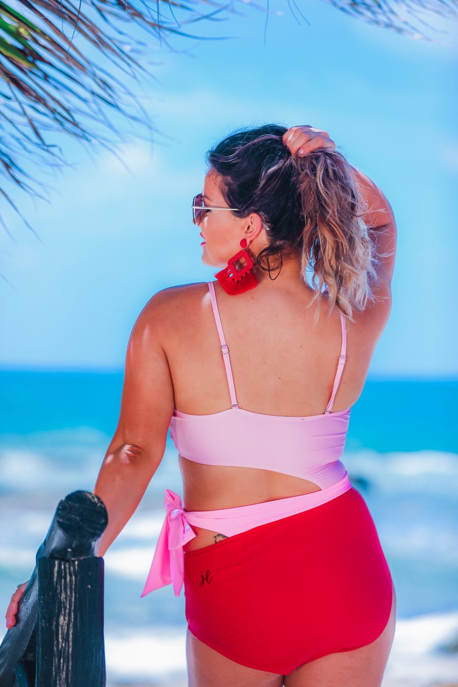 two-tone one-piece swimsuit made of stretchy material with adjustable spaghetti straps that can crisscross in back, a side cutout with a wraparound tie, and removable padding