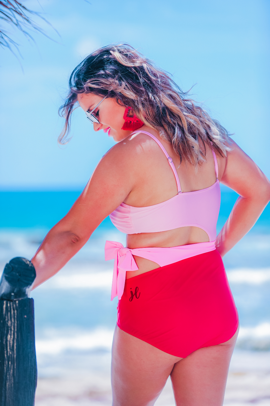 two-tone one-piece swimsuit made of stretchy material with adjustable spaghetti straps that can crisscross in back, a side cutout with a wraparound tie, and removable padding