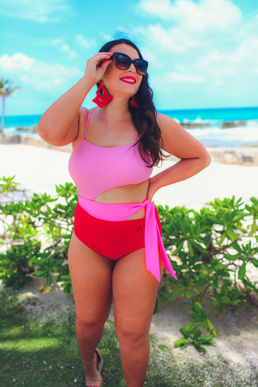two-tone one-piece swimsuit made of stretchy material with adjustable spaghetti straps that can crisscross in back, a side cutout with a wraparound tie, and removable padding