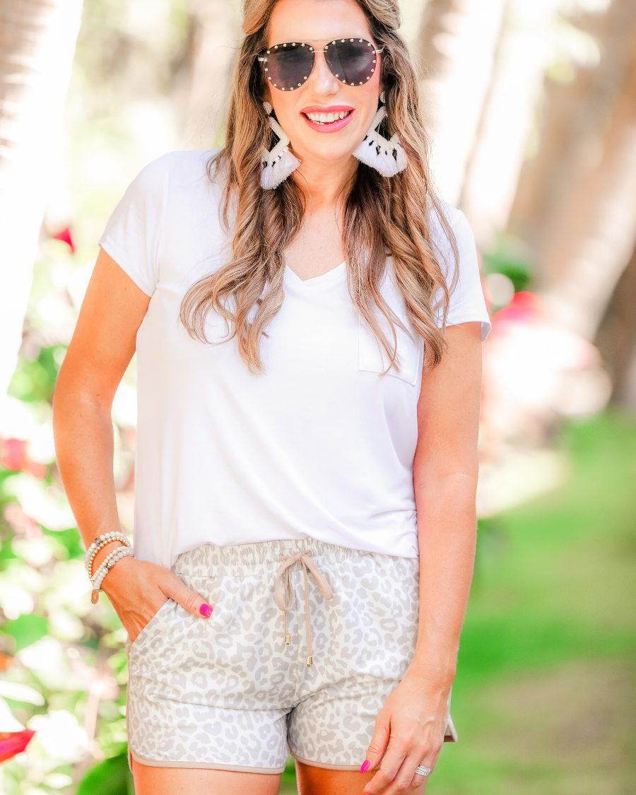 mid-rise relaxed fit activewear shorts with side pockets and a tie waist drawstring with gold bead accents, designed on a neutral leopard pattern print fabric, cream base, and beige trim
