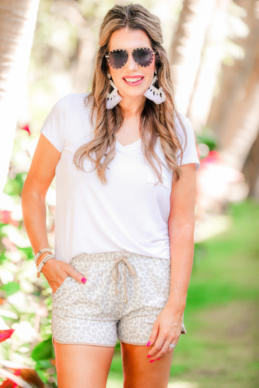 mid-rise relaxed fit activewear shorts with side pockets and a tie waist drawstring with gold bead accents, designed on a neutral leopard pattern print fabric, cream base, and beige trim