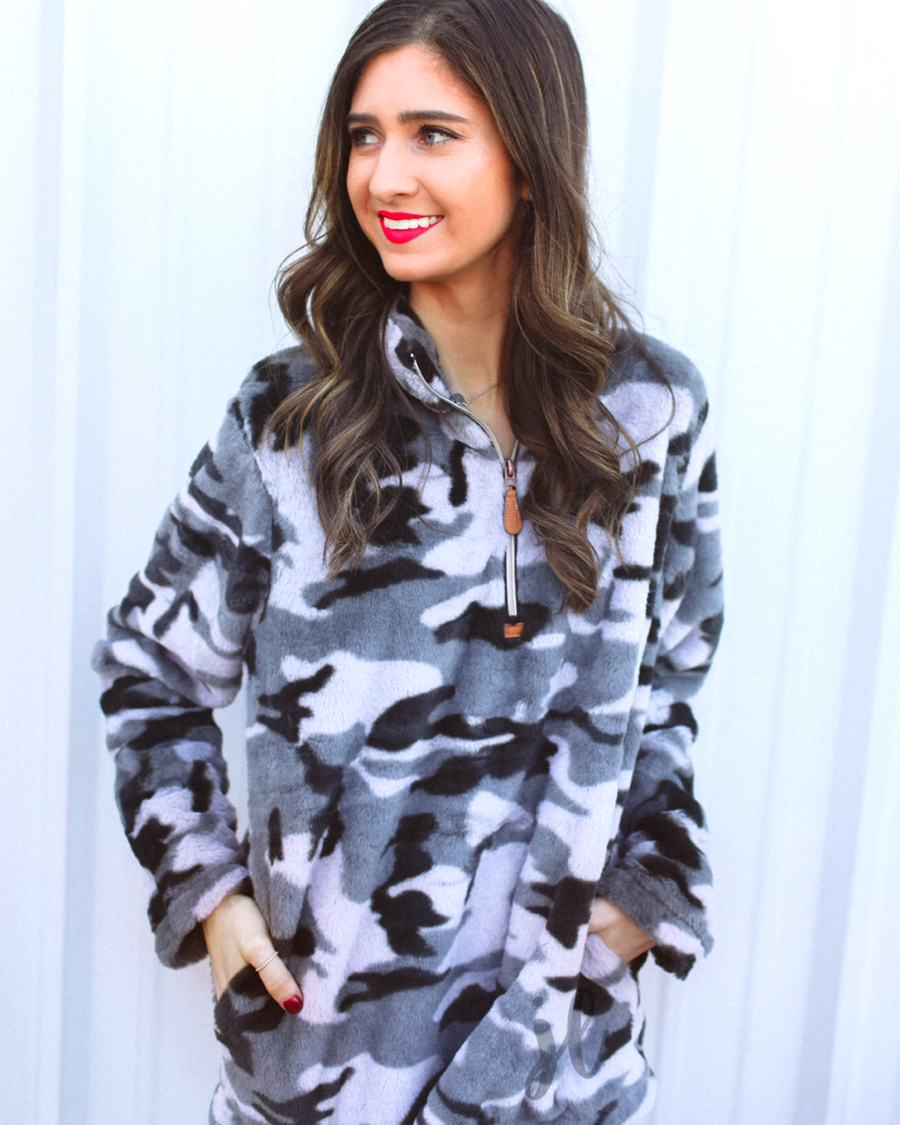 a long-sleeve luxurious faux fur material with a quarter zip, front pockets, and a foldable collar on a camouflage pattern fabric