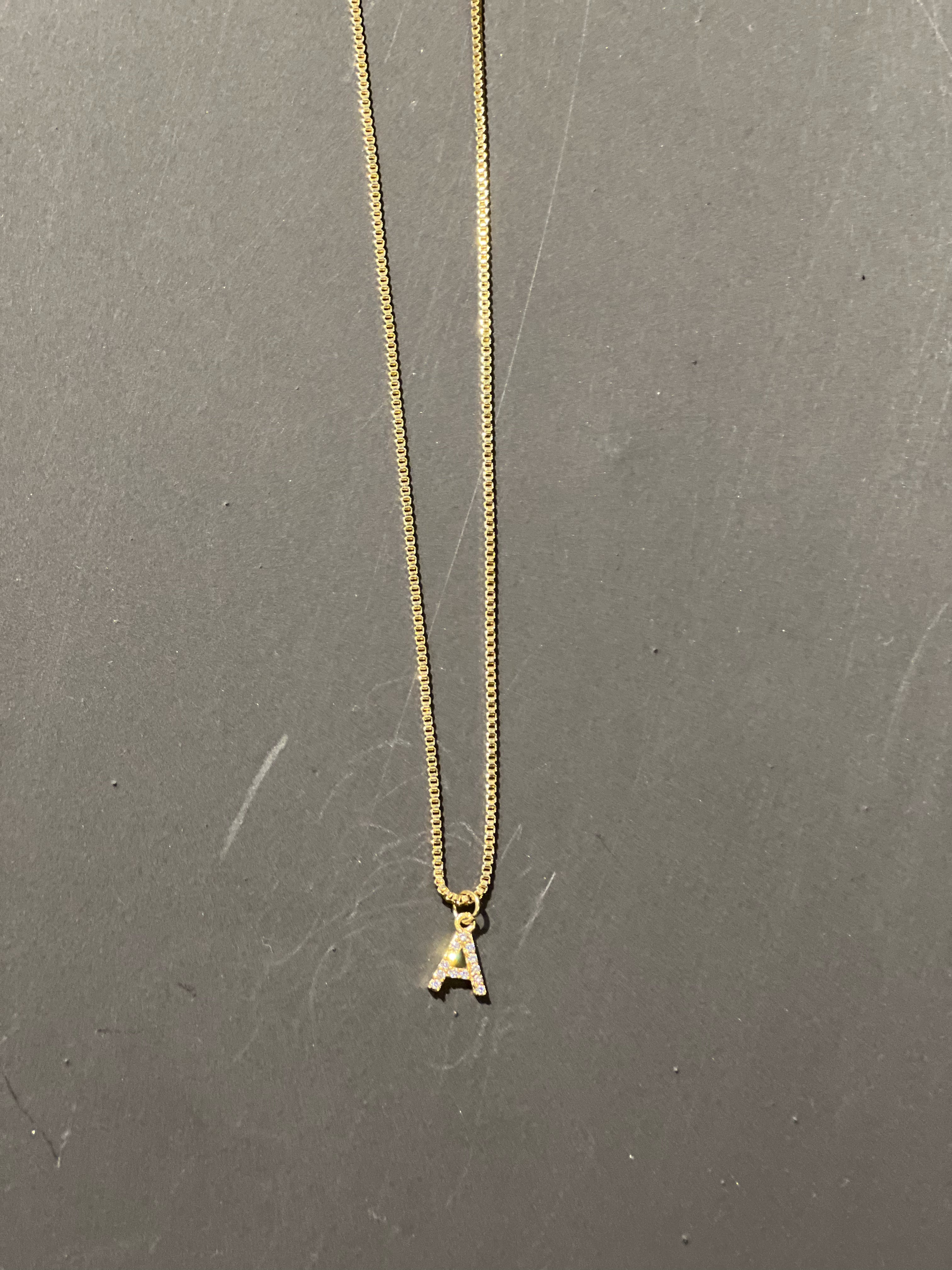 gold chain necklace with rhinestone-studded 'A' initial charm