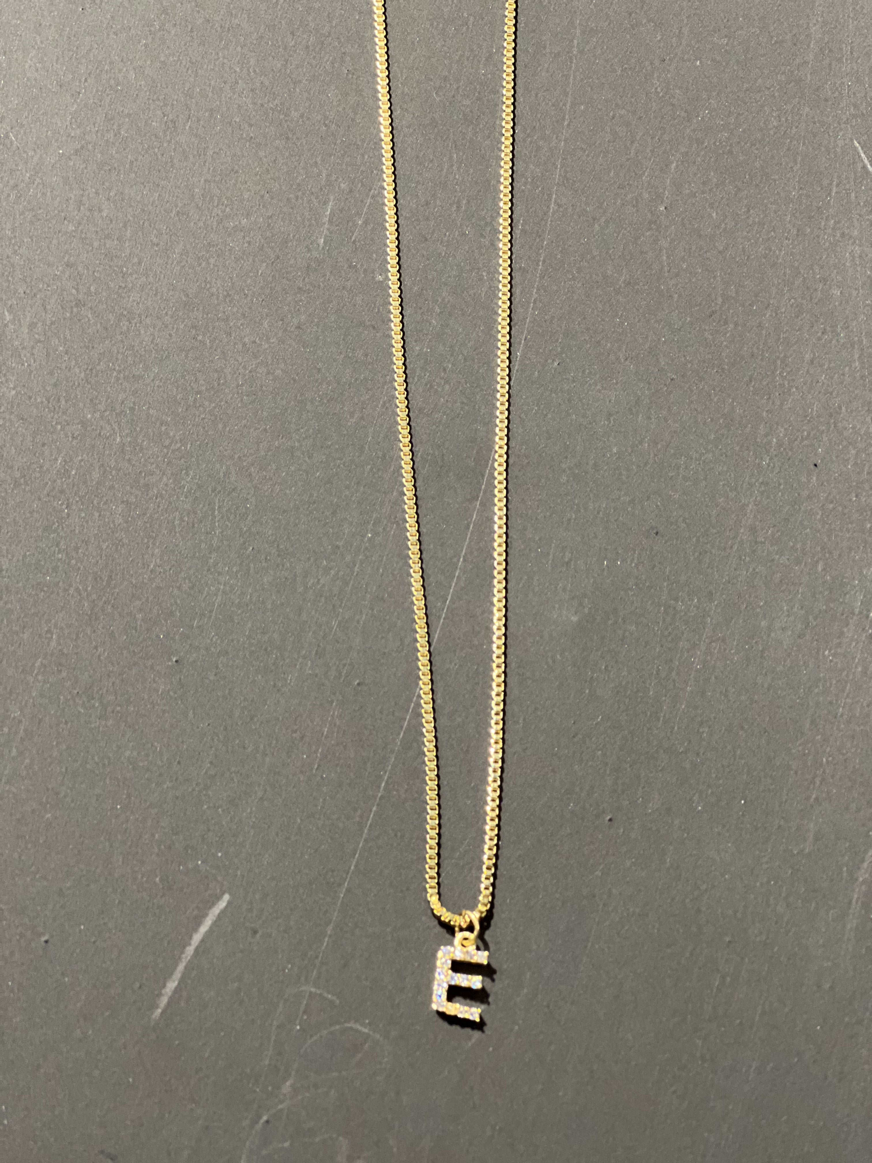 gold chain necklace with rhinestone-studded 'E' initial charm