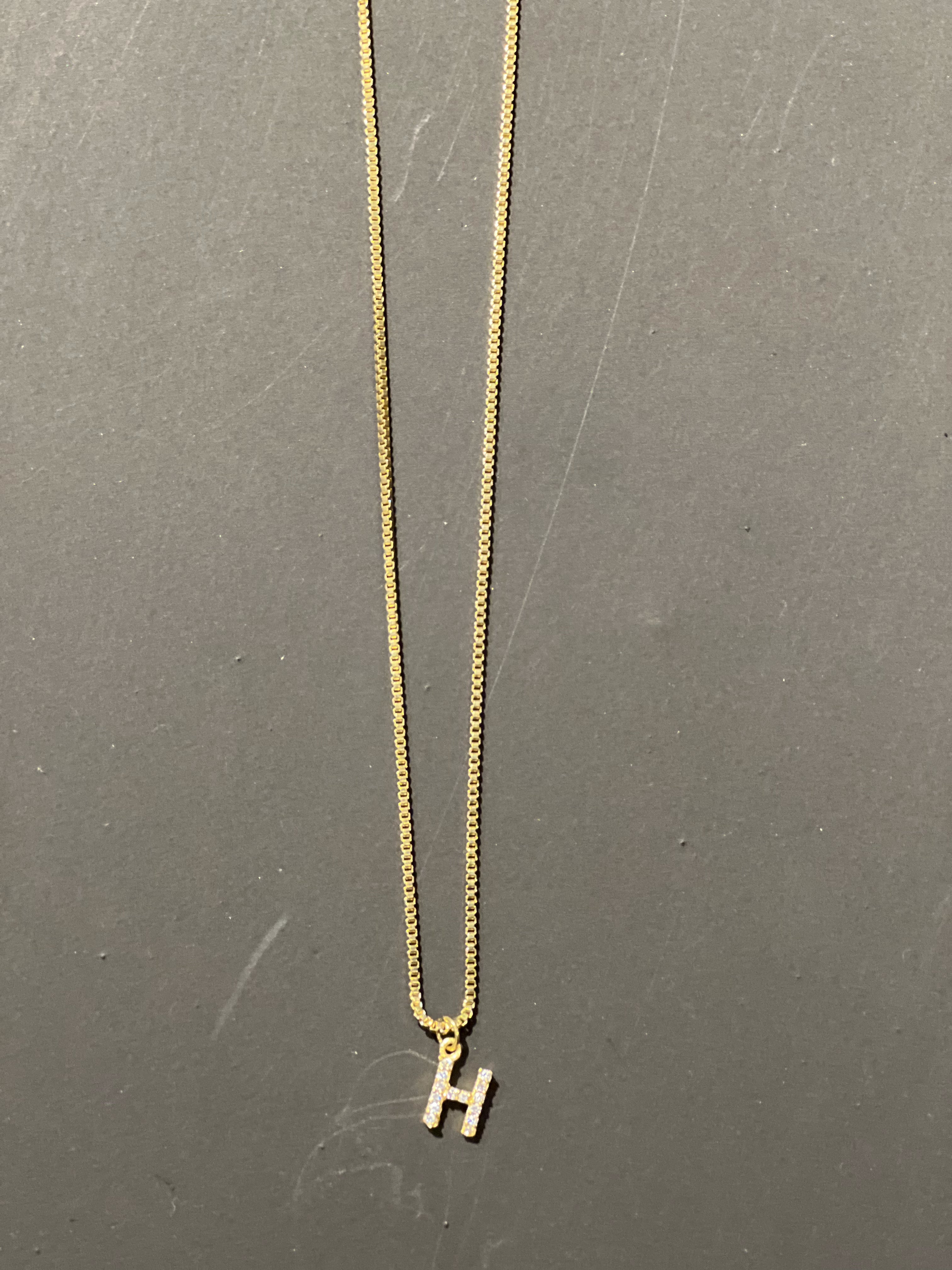 gold chain necklace with rhinestone-studded 'H' initial charm