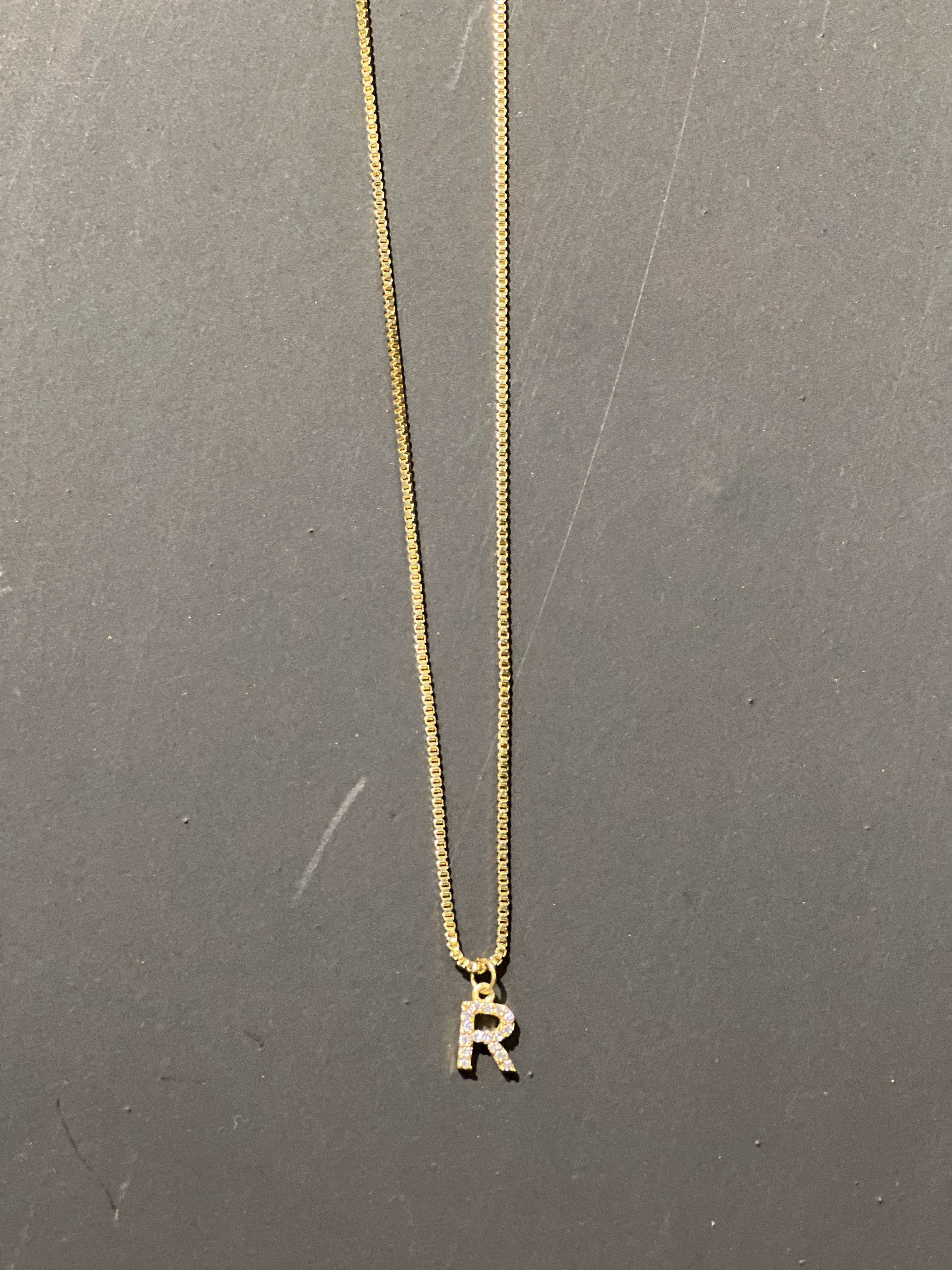 gold chain necklace with rhinestone-studded 'R' initial charm