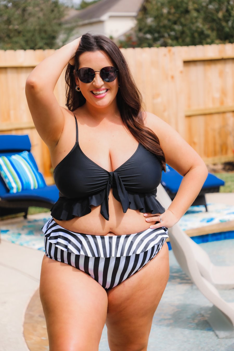 a solid black bikini top with a front tie, ruffle trim, and adjustable spaghetti straps paired with a vertical black and white full-coverage bottom with ruffle trim