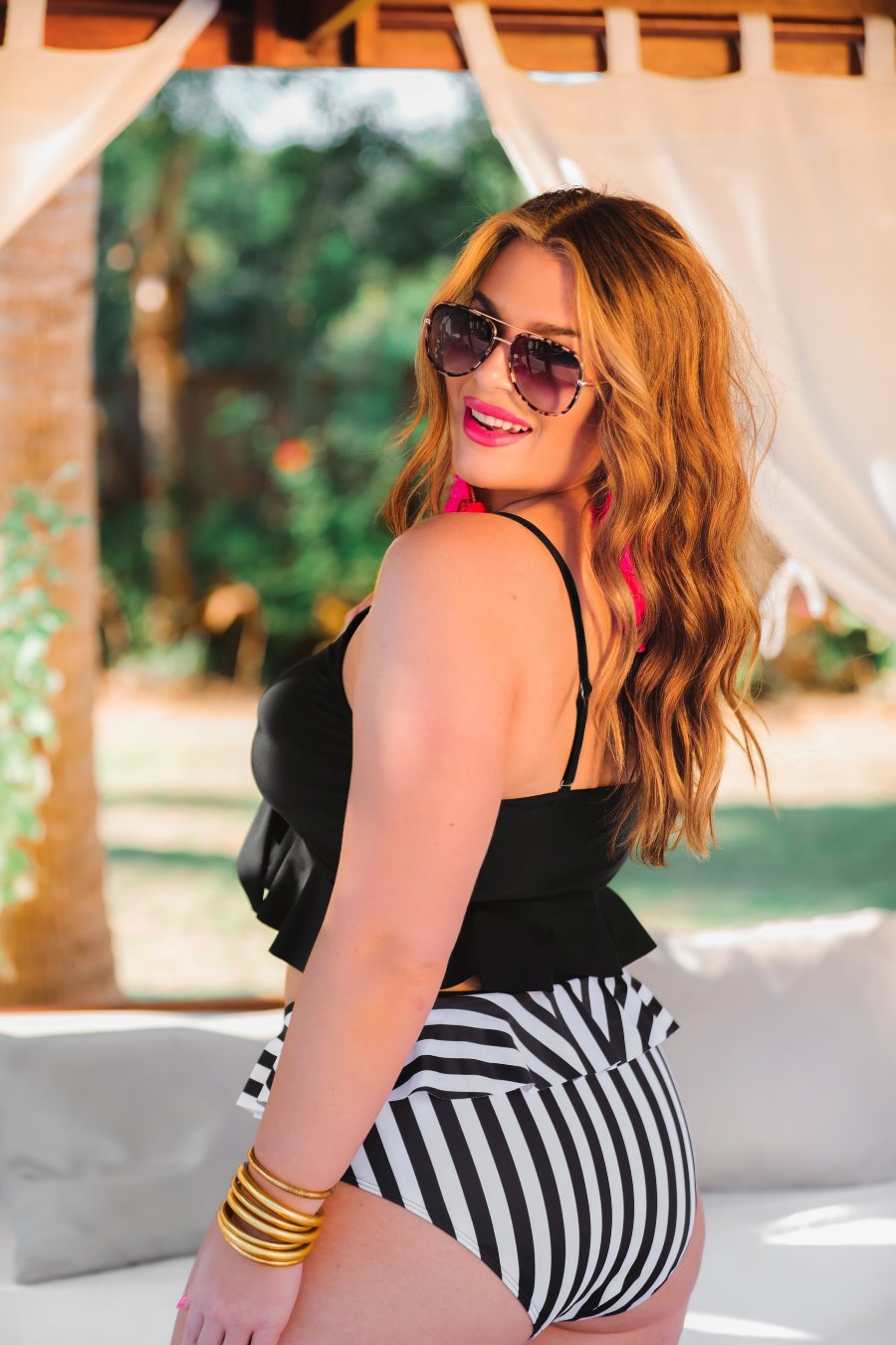 a solid black bikini top with a front tie, ruffle trim, and adjustable spaghetti straps paired with a vertical black and white full-coverage bottom with ruffle trim