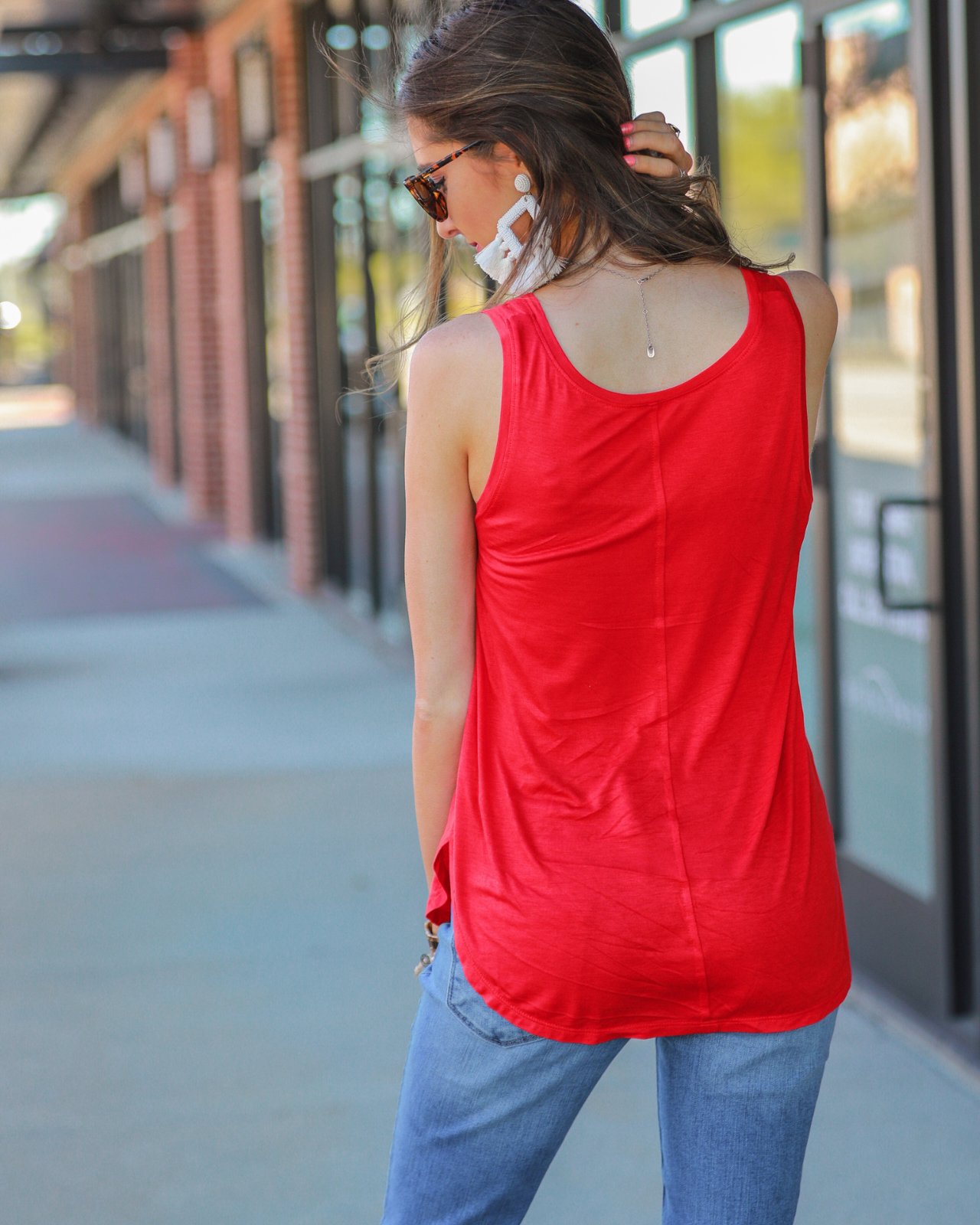 a sleeveless style tank with a v-neck neckline, side slits, a back center seam, and a rounded hi-lo hemline in red