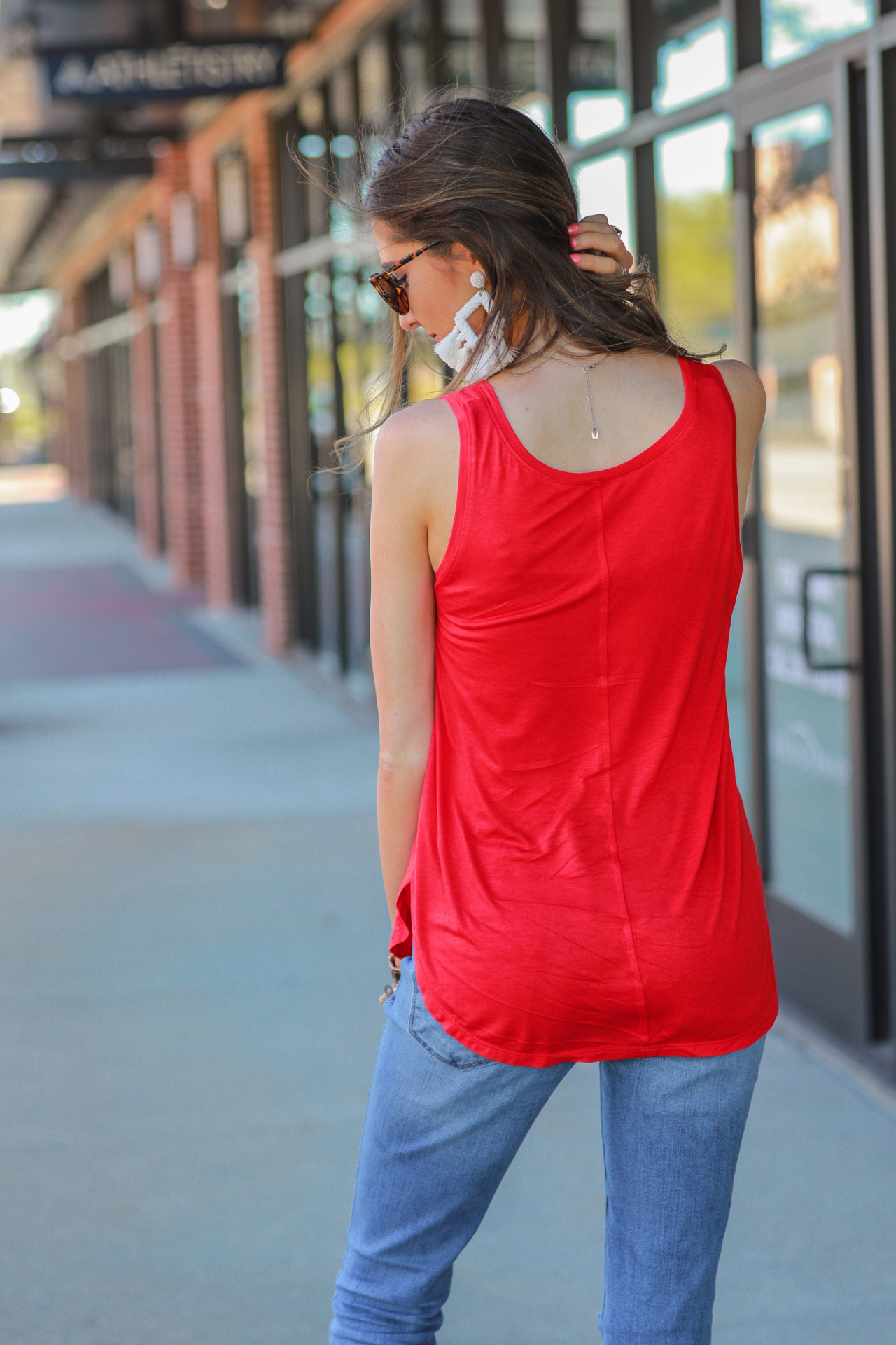 a sleeveless style tank with a v-neck neckline, side slits, a back center seam, and a rounded hi-lo hemline in red