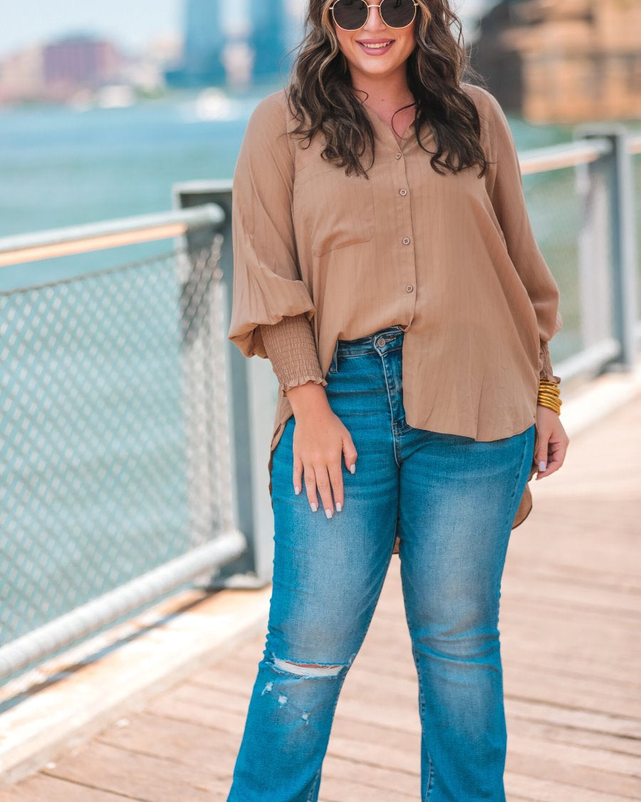 long-sleeve unlined top with a collared neckline, smocked wrists, button down front closure, functional side pockets, a chest pocket, a high-low hemline, and a relaxed fit designed on vertical stripe fabric in taupe