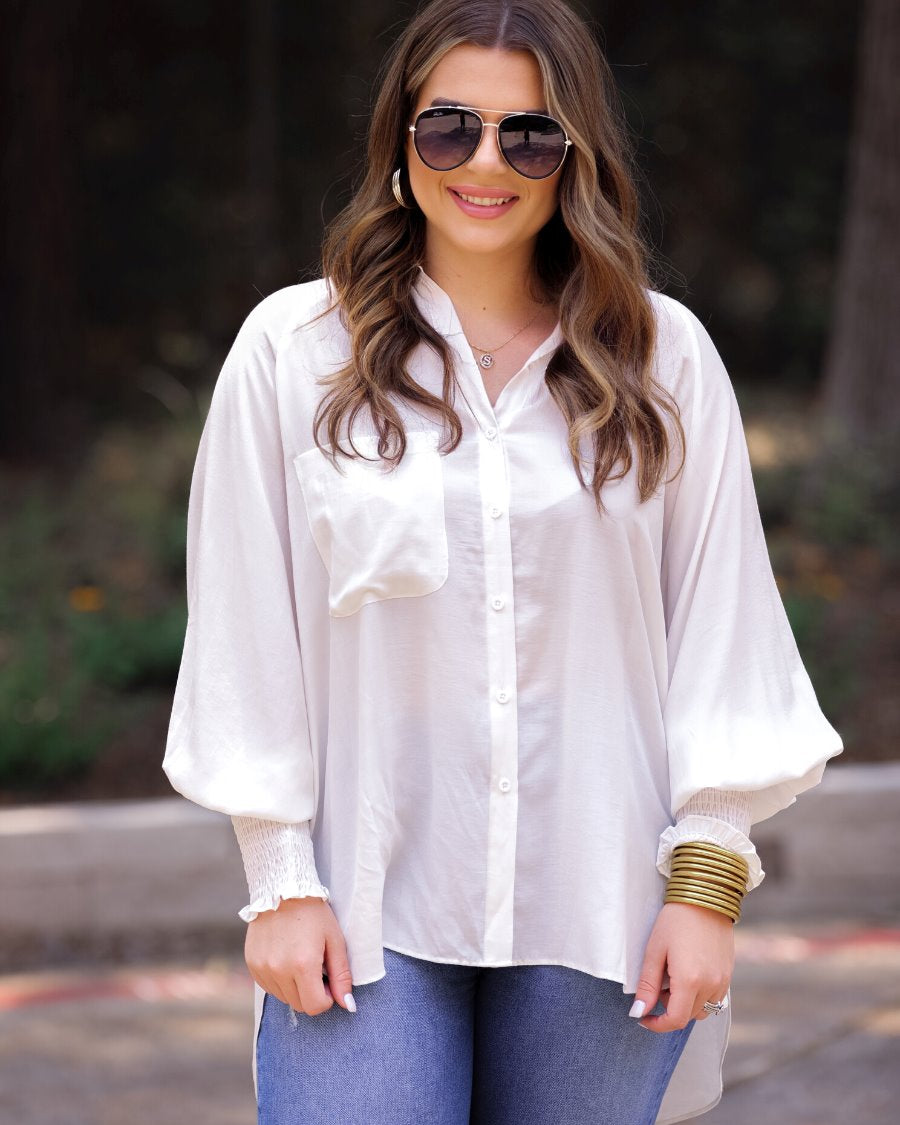 long-sleeve unlined top with a collared neckline, smocked wrists, button down front closure, functional side pockets, a chest pocket, a high-low hemline, and a relaxed fit designed on vertical stripe fabric in ivory
