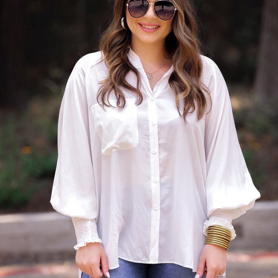 long-sleeve unlined top with a collared neckline, smocked wrists, button down front closure, functional side pockets, a chest pocket, a high-low hemline, and a relaxed fit designed on vertical stripe fabric in ivory