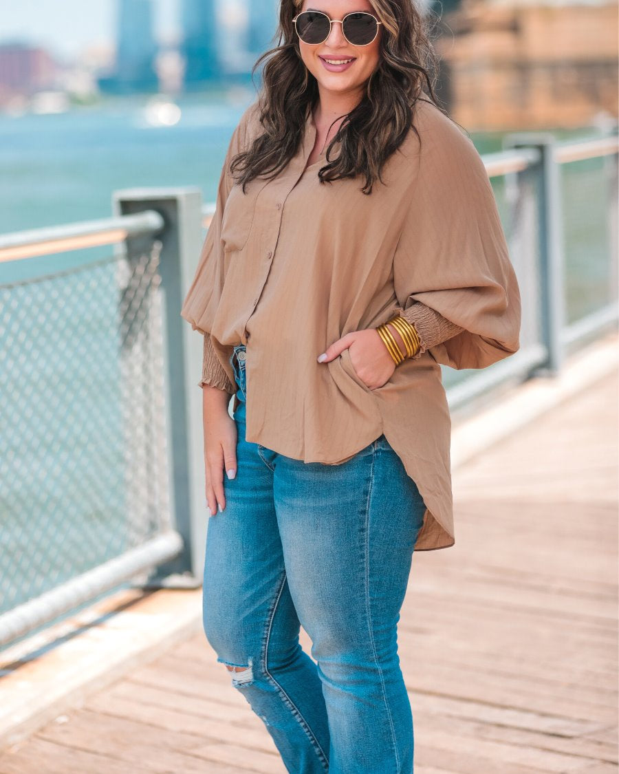 long-sleeve unlined top with a collared neckline, smocked wrists, button down front closure, functional side pockets, a chest pocket, a high-low hemline, and a relaxed fit designed on vertical stripe fabric in taupe