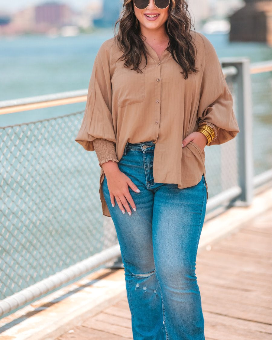 long-sleeve unlined top with a collared neckline, smocked wrists, button down front closure, functional side pockets, a chest pocket, a high-low hemline, and a relaxed fit designed on vertical stripe fabric in taupe