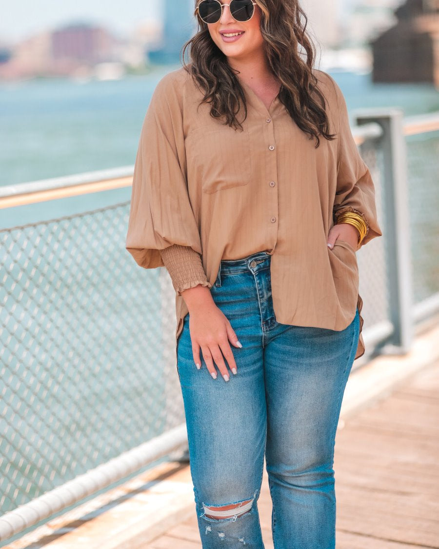 long-sleeve unlined top with a collared neckline, smocked wrists, button down front closure, functional side pockets, a chest pocket, a high-low hemline, and a relaxed fit designed on vertical stripe fabric in taupe