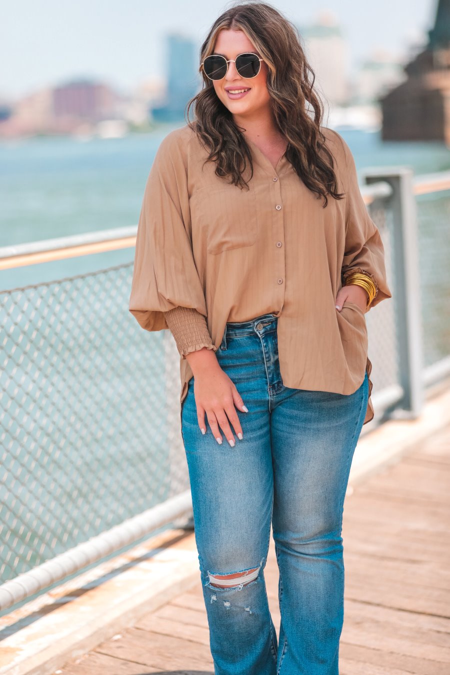 long-sleeve unlined top with a collared neckline, smocked wrists, button down front closure, functional side pockets, a chest pocket, a high-low hemline, and a relaxed fit designed on vertical stripe fabric in taupe