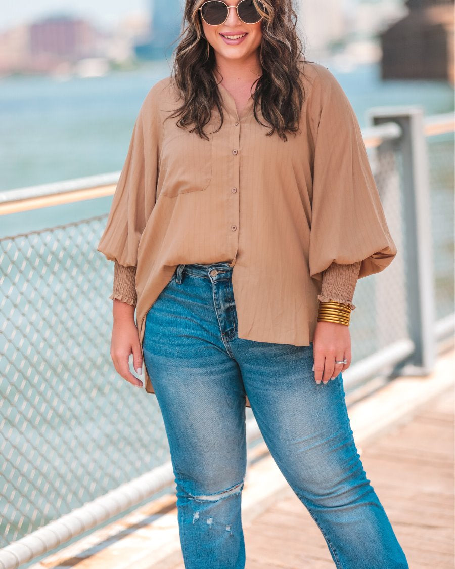 long-sleeve unlined top with a collared neckline, smocked wrists, button down front closure, functional side pockets, a chest pocket, a high-low hemline, and a relaxed fit designed on vertical stripe fabric in taupe