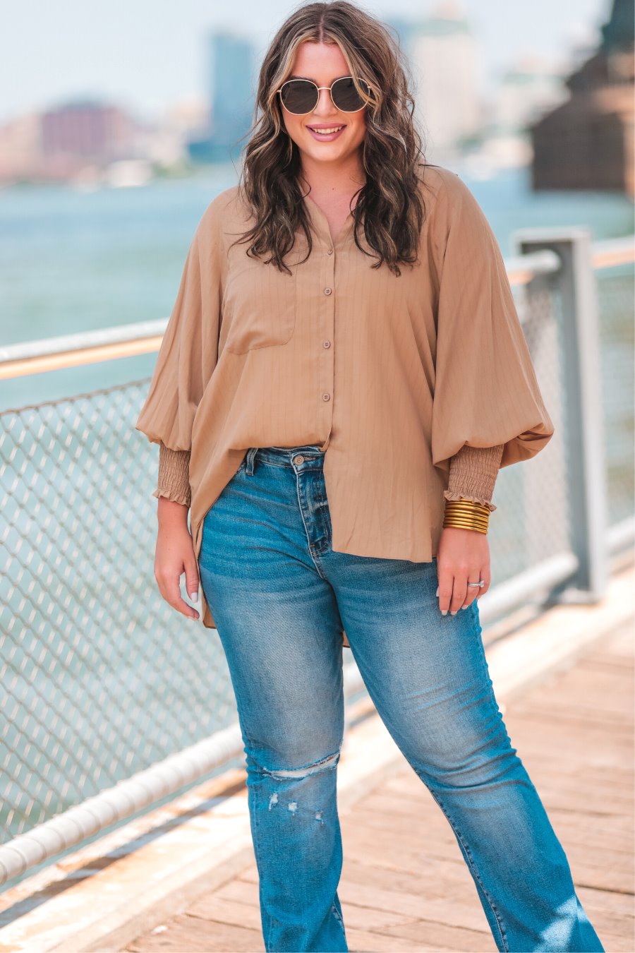 long-sleeve unlined top with a collared neckline, smocked wrists, button down front closure, functional side pockets, a chest pocket, a high-low hemline, and a relaxed fit designed on vertical stripe fabric in taupe