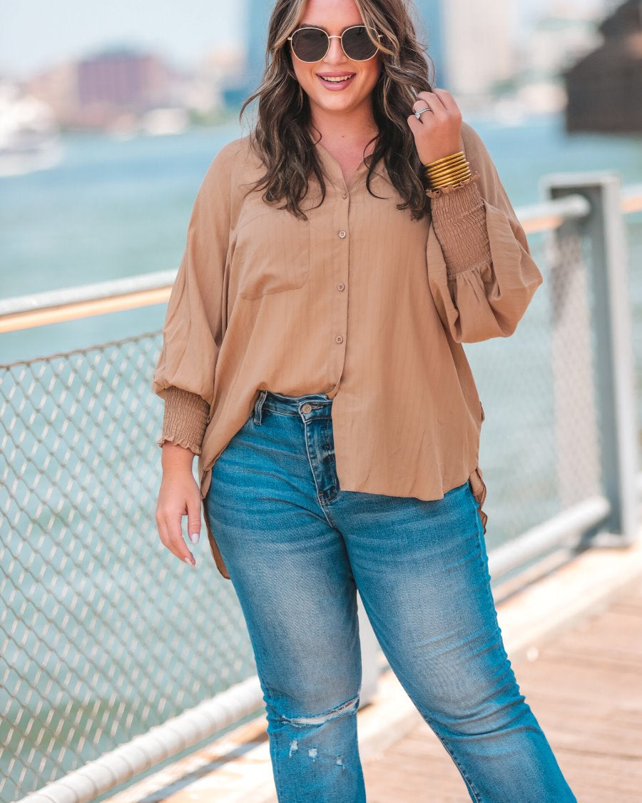 long-sleeve unlined top with a collared neckline, smocked wrists, button down front closure, functional side pockets, a chest pocket, a high-low hemline, and a relaxed fit designed on vertical stripe fabric in taupe
