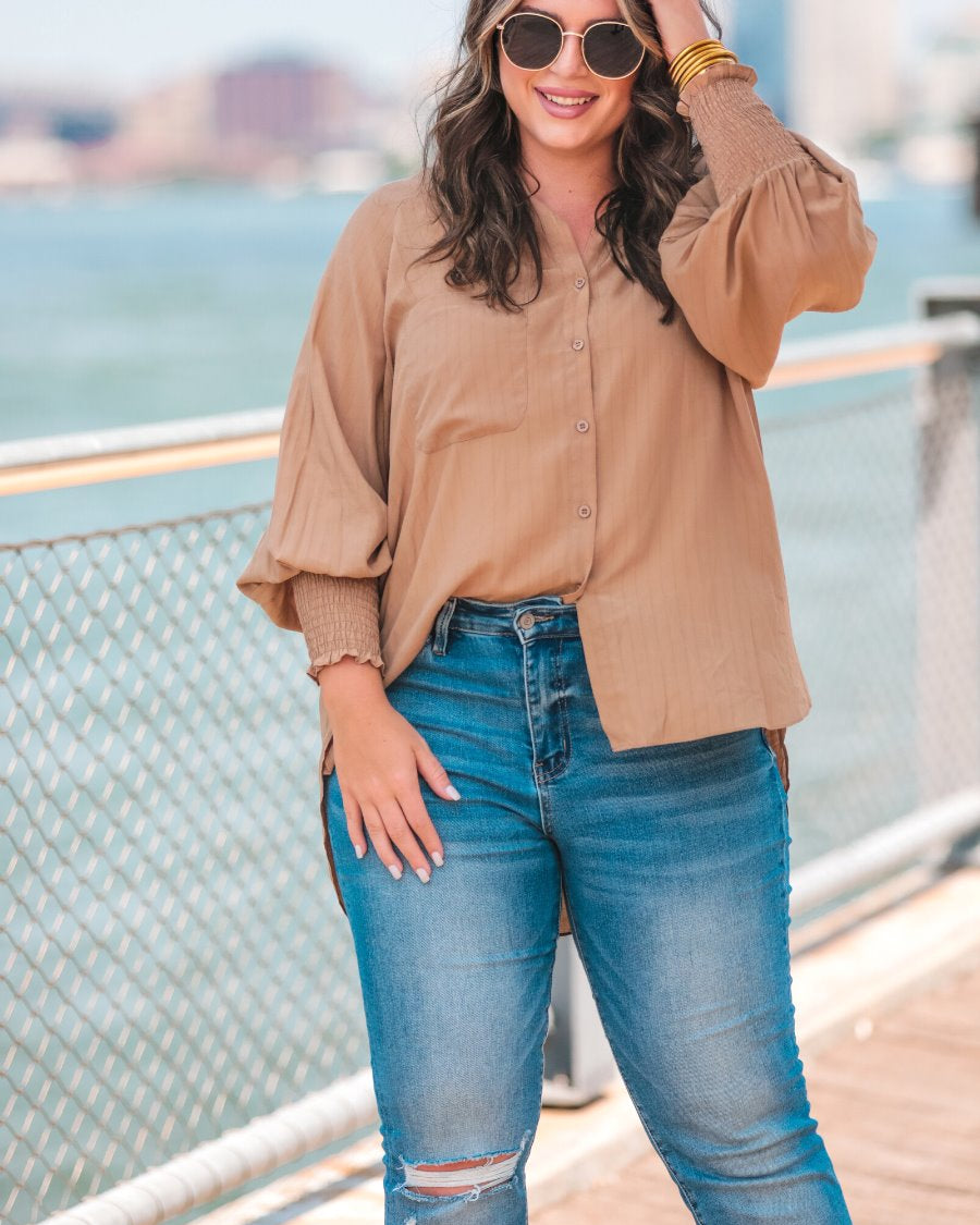 long-sleeve unlined top with a collared neckline, smocked wrists, button down front closure, functional side pockets, a chest pocket, a high-low hemline, and a relaxed fit designed on vertical stripe fabric in taupe