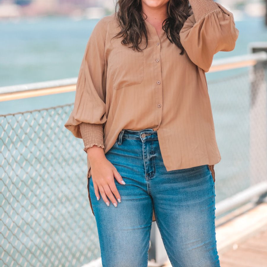 long-sleeve unlined top with a collared neckline, smocked wrists, button down front closure, functional side pockets, a chest pocket, a high-low hemline, and a relaxed fit designed on vertical stripe fabric in taupe