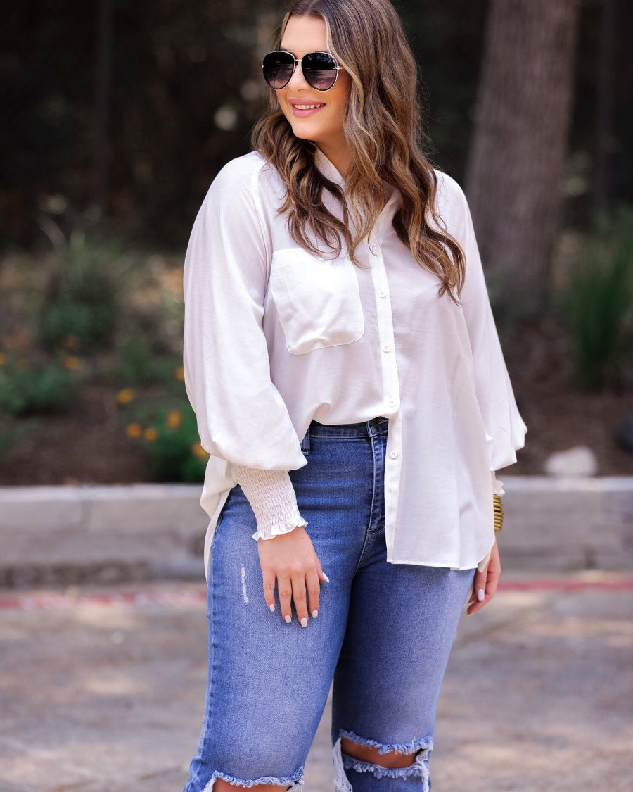 long-sleeve unlined top with a collared neckline, smocked wrists, button down front closure, functional side pockets, a chest pocket, a high-low hemline, and a relaxed fit designed on vertical stripe fabric in ivory