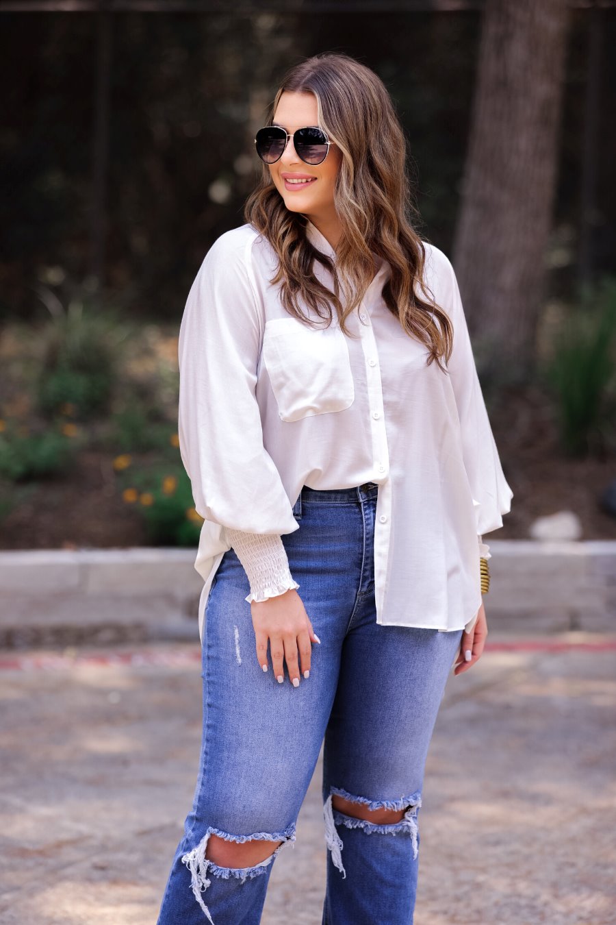 long-sleeve unlined top with a collared neckline, smocked wrists, button down front closure, functional side pockets, a chest pocket, a high-low hemline, and a relaxed fit designed on vertical stripe fabric in ivory