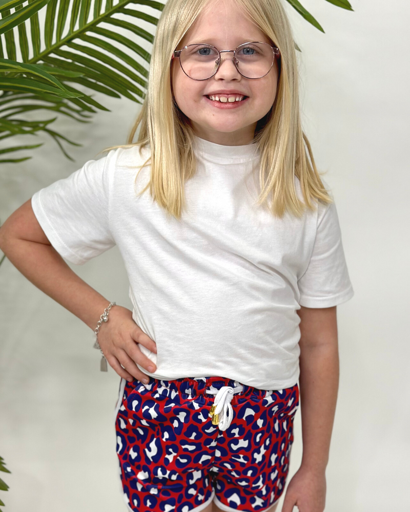 mid-rise relaxed fit activewear shorts with side pockets and a tie waist drawstring with gold bead accents, designed on a vibrant red leopard print and ivory trim