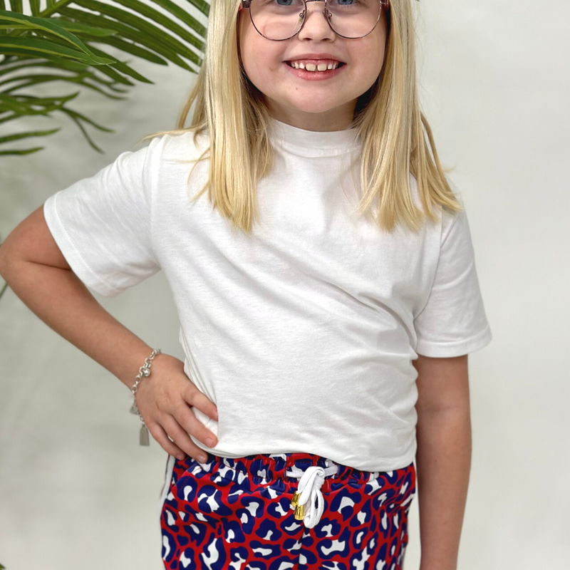 mid-rise relaxed fit activewear shorts with side pockets and a tie waist drawstring with gold bead accents, designed on a vibrant red leopard print and ivory trim