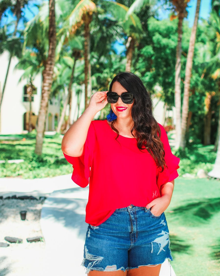 a red true-to-size blouse crafted from lightweight textured fabric with a rounded neckline, tiered ruffle sleeves, and a relaxed drape