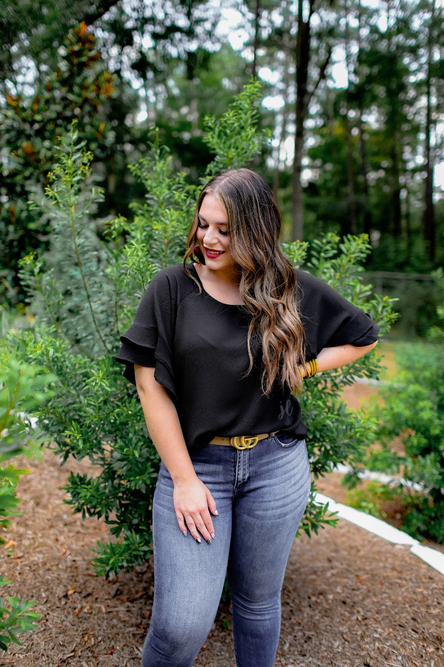 a black true-to-size blouse crafted from lightweight textured fabric with a rounded neckline, tiered ruffle sleeves, and a relaxed drape