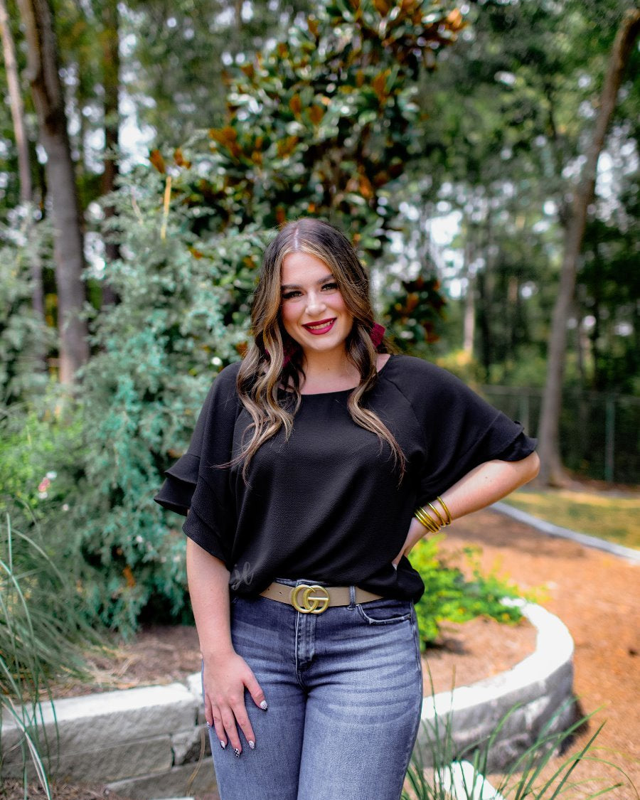 a black true-to-size blouse crafted from lightweight textured fabric with a rounded neckline, tiered ruffle sleeves, and a relaxed drape