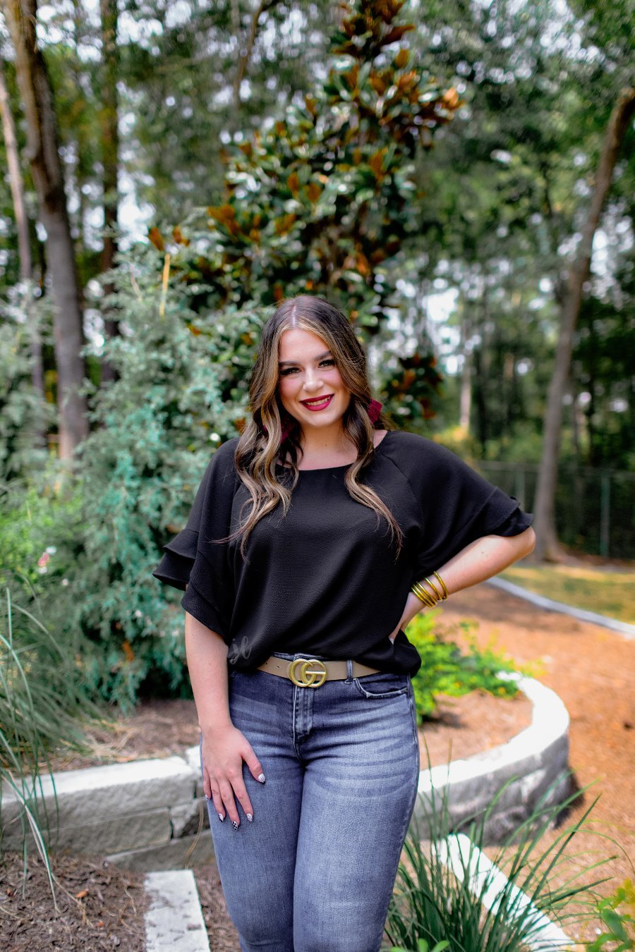 a black true-to-size blouse crafted from lightweight textured fabric with a rounded neckline, tiered ruffle sleeves, and a relaxed drape