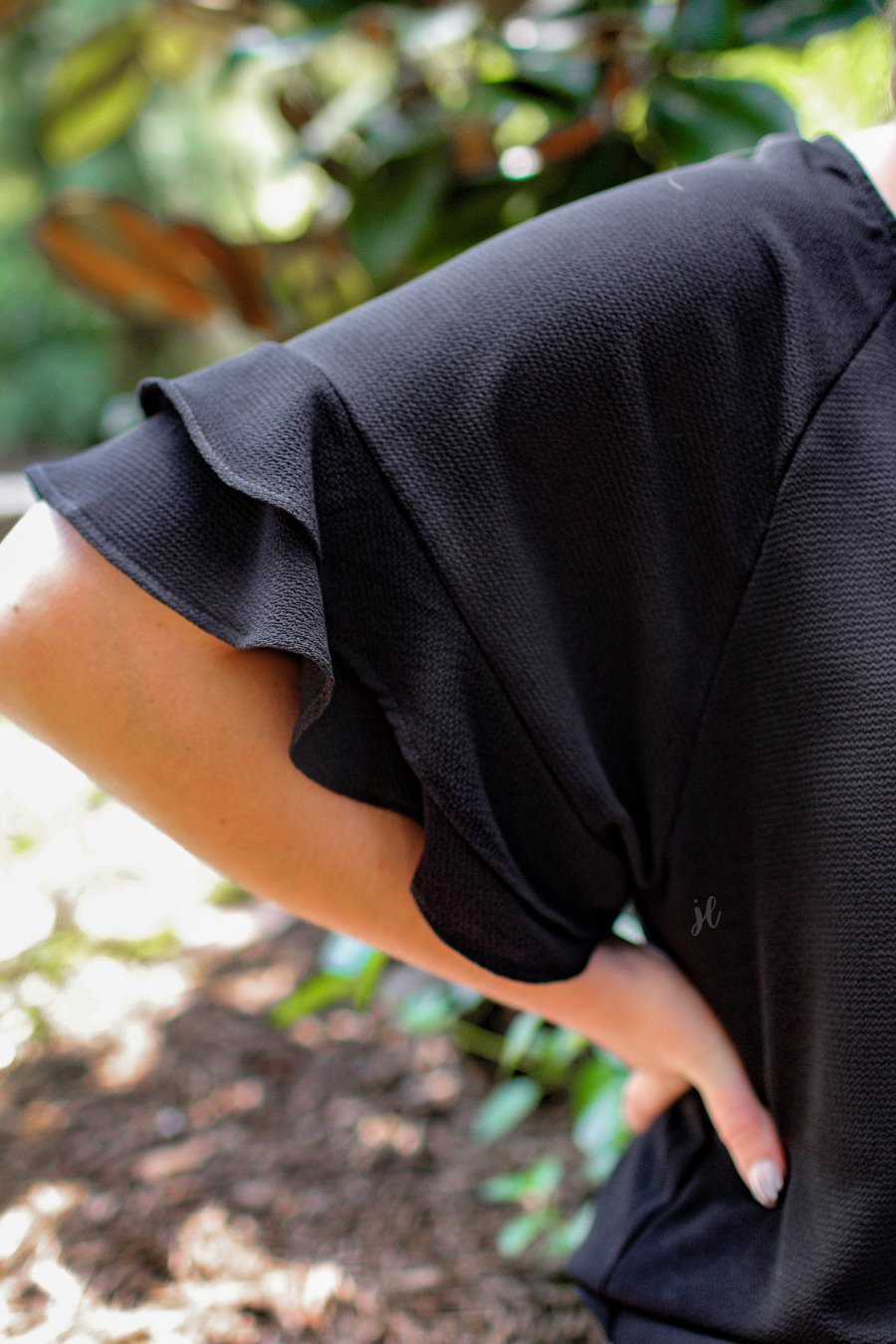 a black true-to-size blouse crafted from lightweight textured fabric with a rounded neckline, tiered ruffle sleeves, and a relaxed drape