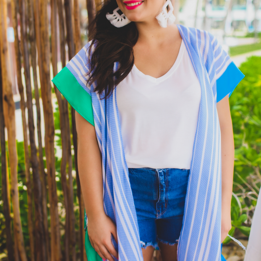 a loose-flowy fit kimono crafted from lightweight fabric with an open-front style, pom pom detailing, colored sides, and contrasting panels