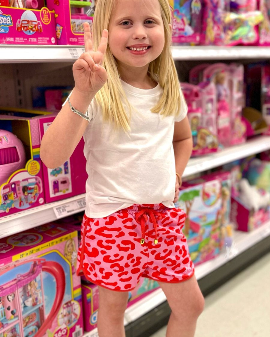 mid-rise relaxed fit activewear shorts with side pockets and a tie waist drawstring with a gold bead accent on a pink leopard print fabric and pink trim