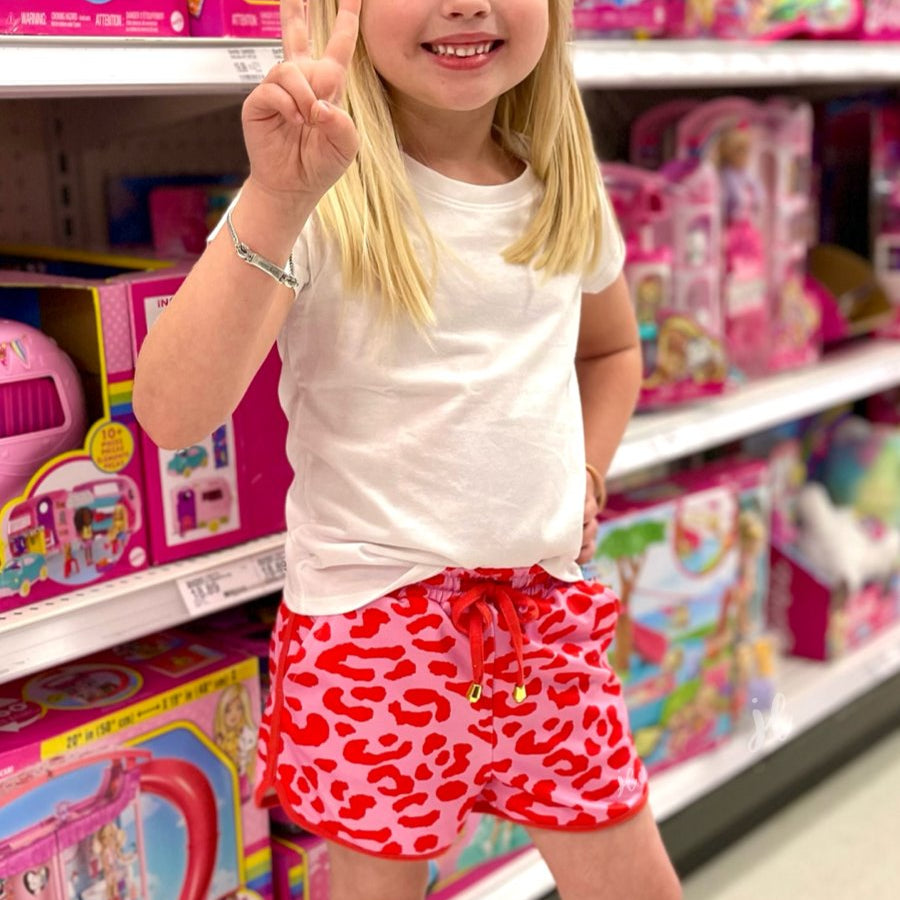 mid-rise relaxed fit activewear shorts with side pockets and a tie waist drawstring with a gold bead accent on a pink leopard print fabric and pink trim
