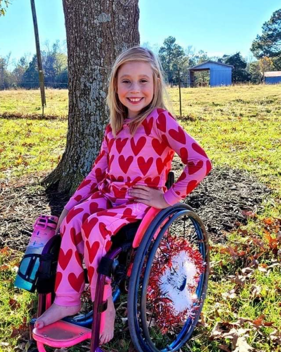 long-sleeve top with red hearts on a solid pink fabric and a rounded neckline paired with matching elastic waistband bottoms