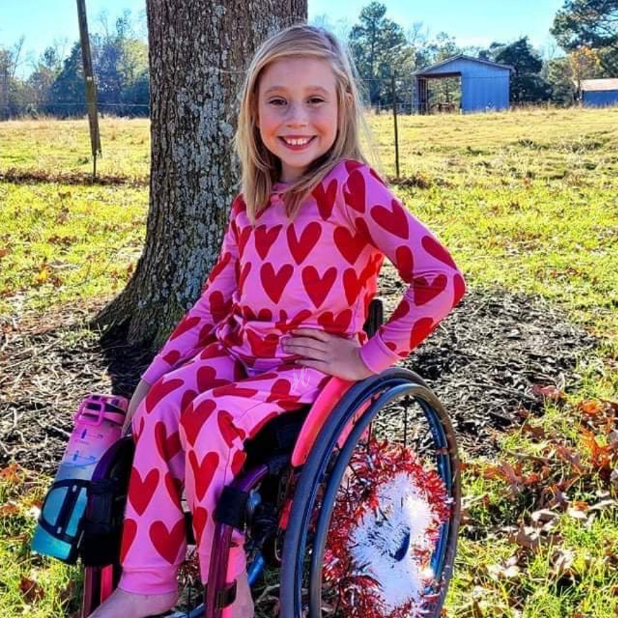 long-sleeve top with red hearts on a solid pink fabric and a rounded neckline paired with matching elastic waistband bottoms