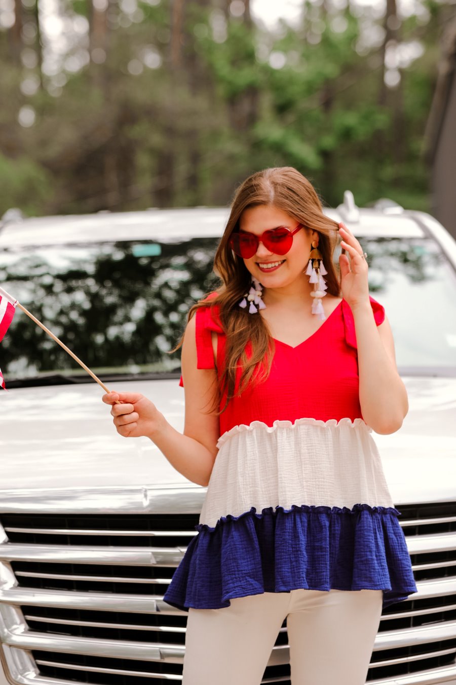 a red tiered color block top with a V-neckline front and back, adjustable wide tie straps, a ruffled hem, and a relaxed, lightweight fit